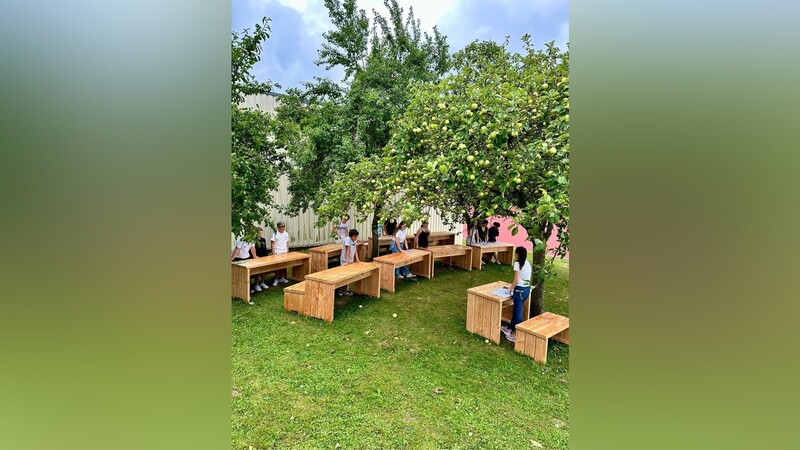 Natürlich durften auch die Schüler gleich auf den neuen Schulmöbeln im Grünen Platz nehmen, die idyllisch unter Obstbäumen stehen.
