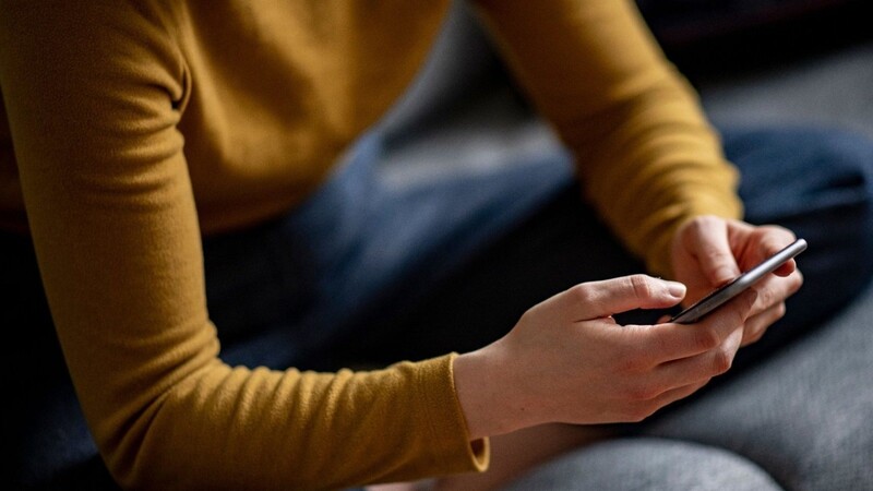 Eine Frau hält ein Smartphone in den Händen.