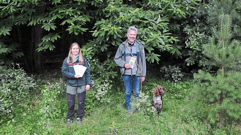 Johanna Gierl und Forstdirektor Dr. Arthur Bauer (mit Hündin Dora) präsentieren unter einer prächtigen Edelkastanie im Wald bei Grafenwiesen die Flyer für die Veranstaltungsreihe für Frauen "Die Waldbewirtschaftung im Lauf der Jahreszeiten".